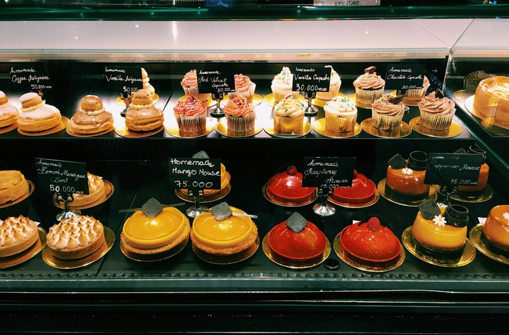 An enticing display of homemade cupcakes and pastries in a bakery showcase, perfect for dessert enthusiasts.